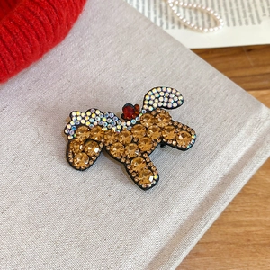 Close-up of champagne crystal studded dog brooch on festive red knit background