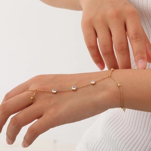 Detail of a gold finger bracelet with four clear crystals on a female model's hand