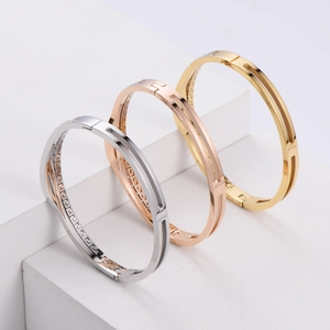 Three-color geometric stainless steel bangles with sparkling zircon on a white pedestal