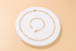 Detailed view of golden link chain necklace and bracelet set on a white display stand