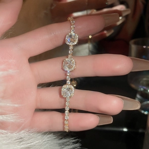 Détail de trois pierres carrées sur un bracelet doré ajustable orné de zircons brillants