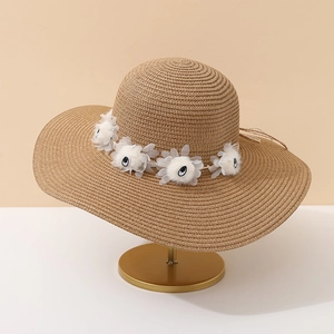Détail d'un chapeau de soleil en paille à larges bords avec fleurs 3D décoratives