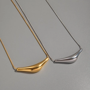 Gros plan de pendentifs géométriques or et argent sur chaînes serpent au style minimaliste
