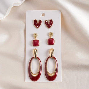 Detail of a 3-pair earring set featuring red enamel hearts and golden geometric shapes