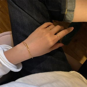 Close-up of minimalist gold chain bracelet and adjustable rings on wrist in a lifestyle view