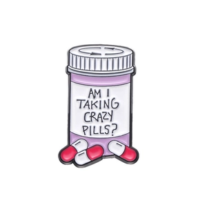 Cartoon enamel pill bottle badge with 'Am I Taking Crazy Pills?' text and red capsules