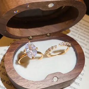 Elegant gold oval zircon ring set with curved diamond band in a wooden jewelry box