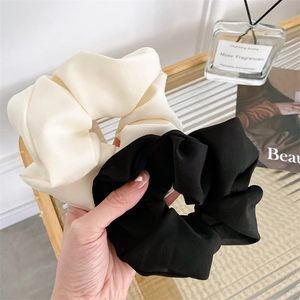 Detail of premium satin scrunchies set in black and white with high-gloss fabric texture