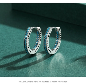 Detailed macro of silver hoop earrings featuring blue turquoise stones and heart engravings