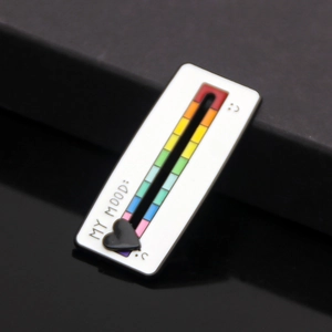 Macro view of a rainbow mood tracker pin with a sliding black heart on a dark background
