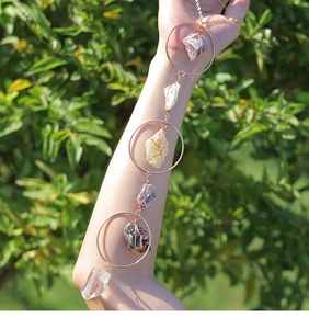 Detailed shot of amethyst and citrine crystal suncatcher held against green plants