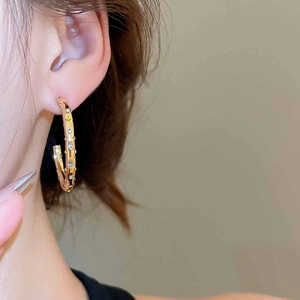 Gros plan de boucles d'oreilles créoles dorées en C avec pierres colorées