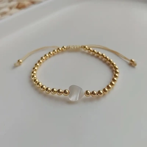 Adjustable gold beaded bracelet featuring a white shell heart charm for women