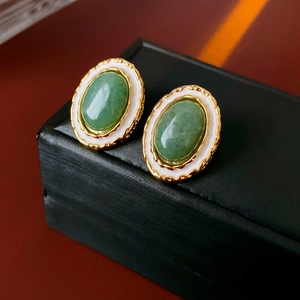 Detail of vintage round stud earrings with green jade stone and gold enamel border