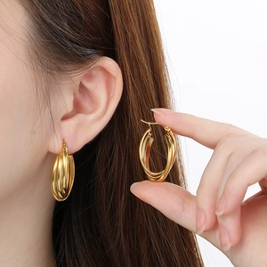 Close-up of gold irregular triple hoop earrings worn on ear showing 3D layered design
