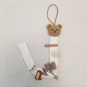Detailed view of white canvas hair clip organizer with plush bear and floral accents