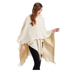 Dettaglio del poncho in maglia beige con morbide nappe e tessuto acrilico di qualità