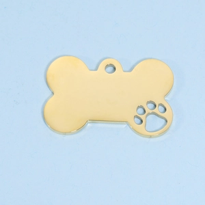 Macro detail of golden bone-shaped metal pet tag featuring a hollow paw print cutout