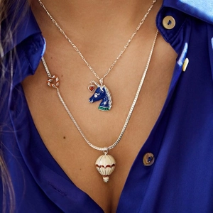 Enameled unicorn and hot air balloon pendant necklaces worn on a silver chain