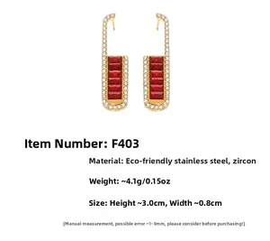 Macro detail of U-shaped gold earrings with red rectangle stones and zircon pavé