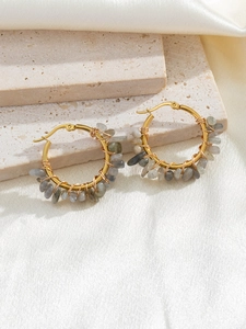 Detailed macro of gold-plated hoop earrings with hand-wrapped natural grey-blue stones
