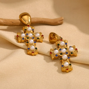 Detailed view of vintage gold cross earrings with baroque pearls and colored crystals