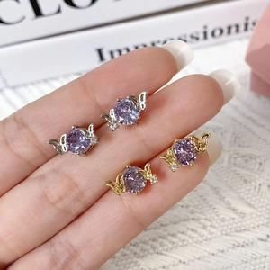 Close-up of gold and silver butterfly earrings featuring round purple zircon center stones