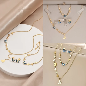 Elegant gold butterfly jewelry set with blue enamel accents on necklace, bracelet and earrings