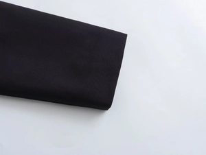 Close-up of black casual jacket cuff showing high-quality fabric and golden button detail