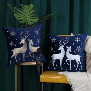 Detailed view of two navy velvet Christmas pillow covers with gold reindeer embroidery