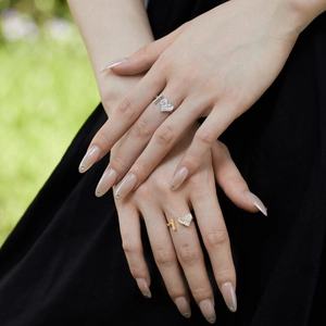 Detail of adjustable silver and gold heart rings with zircon inlay on female hands