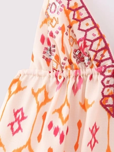 Détails d'un haut femme à imprimé abstrait orange avec sequins argentés et broderies