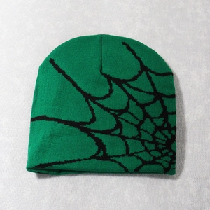 Close-up of green and black knitted beanie showing detailed spider web jacquard texture