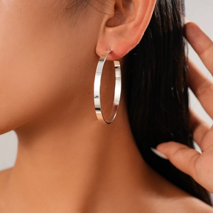 Model wearing large silver geometric hoop earrings with polished metallic finish