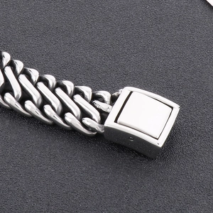 Macro detail of silver stainless steel Cuban link bracelet with square plug-in clasp