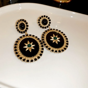 Macro shot of vintage style earrings with black rhinestones and green star center