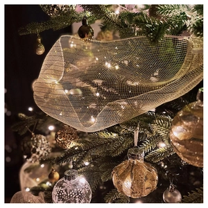 Close-up of golden mesh ribbon and festive ornaments decorating a Christmas tree