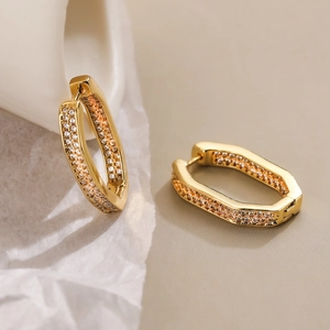 Close-up of geometric gold-plated hexagonal earrings with pavé set zircon crystals