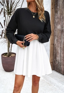 Détail de la robe bicolore avec haut noir à manches longues et jupe plissée blanche