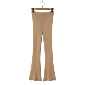Dettaglio dei pantaloni svasati in maglia marrone chiaro con texture a costine e volant