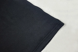 Detail of black knit dress showing professional double-stitch hem and fabric texture