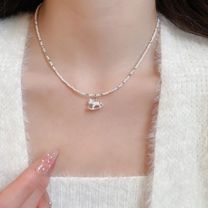 Gros plan d'un collier de perles avec un pendentif cheval à bascule en émail doux