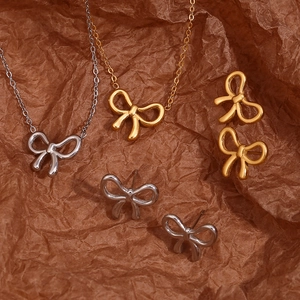 Detail view of 18K gold and silver bow jewelry set on a textured vintage brown background