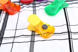 Dettaglio di clip magnetiche colorate e traslucide per alimenti su tessuto a quadretti