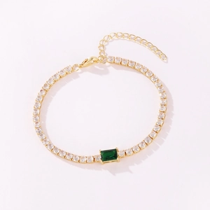 Detailed view of gold bracelet with white cubic zirconia and a green rectangular stone