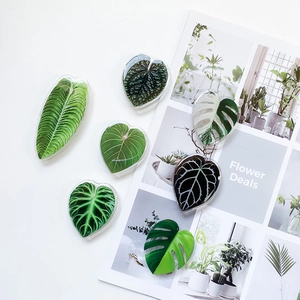 Macro shot of 6 realistic acrylic plant leaf phone grips including Monstera and Anthurium