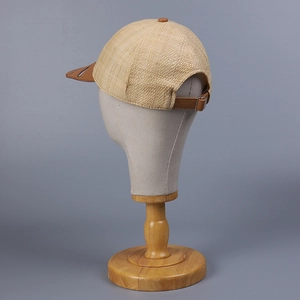 Close-up of raffia straw texture with brown leather brim and metal buckle on baseball cap