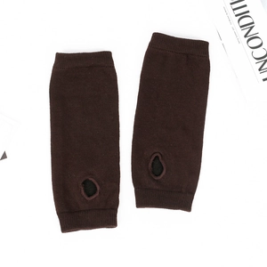 Detail of dark brown knitted arm warmers featuring thumb holes and ribbed cuffs texture