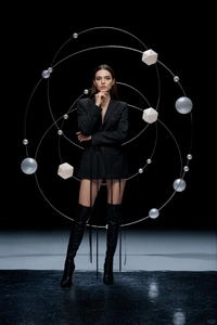 Detail of dark avant-garde blazer dress with long waist straps and black high leather boots