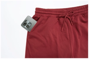 Detail of dark red sweatpants featuring elastic drawstring waist and deep side pocket for phone